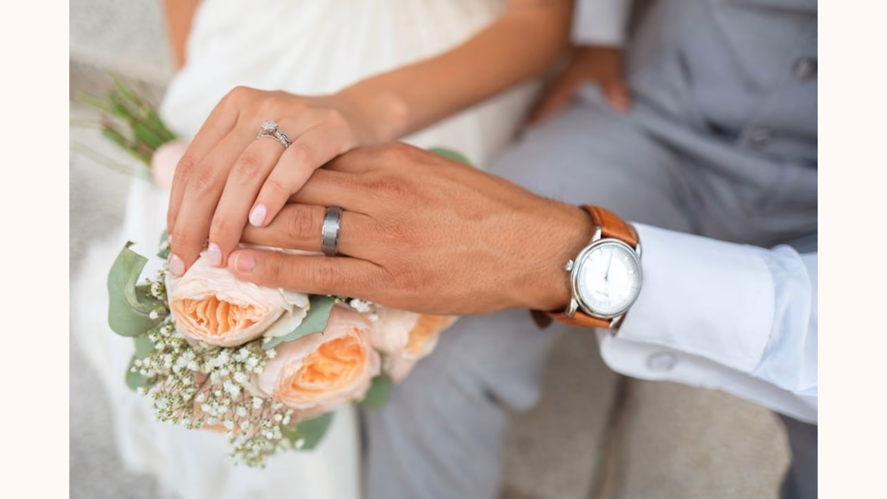 Layar tempat acara menampilkan foto dari tamu: sepasang tangan bercincin di atas buket.
